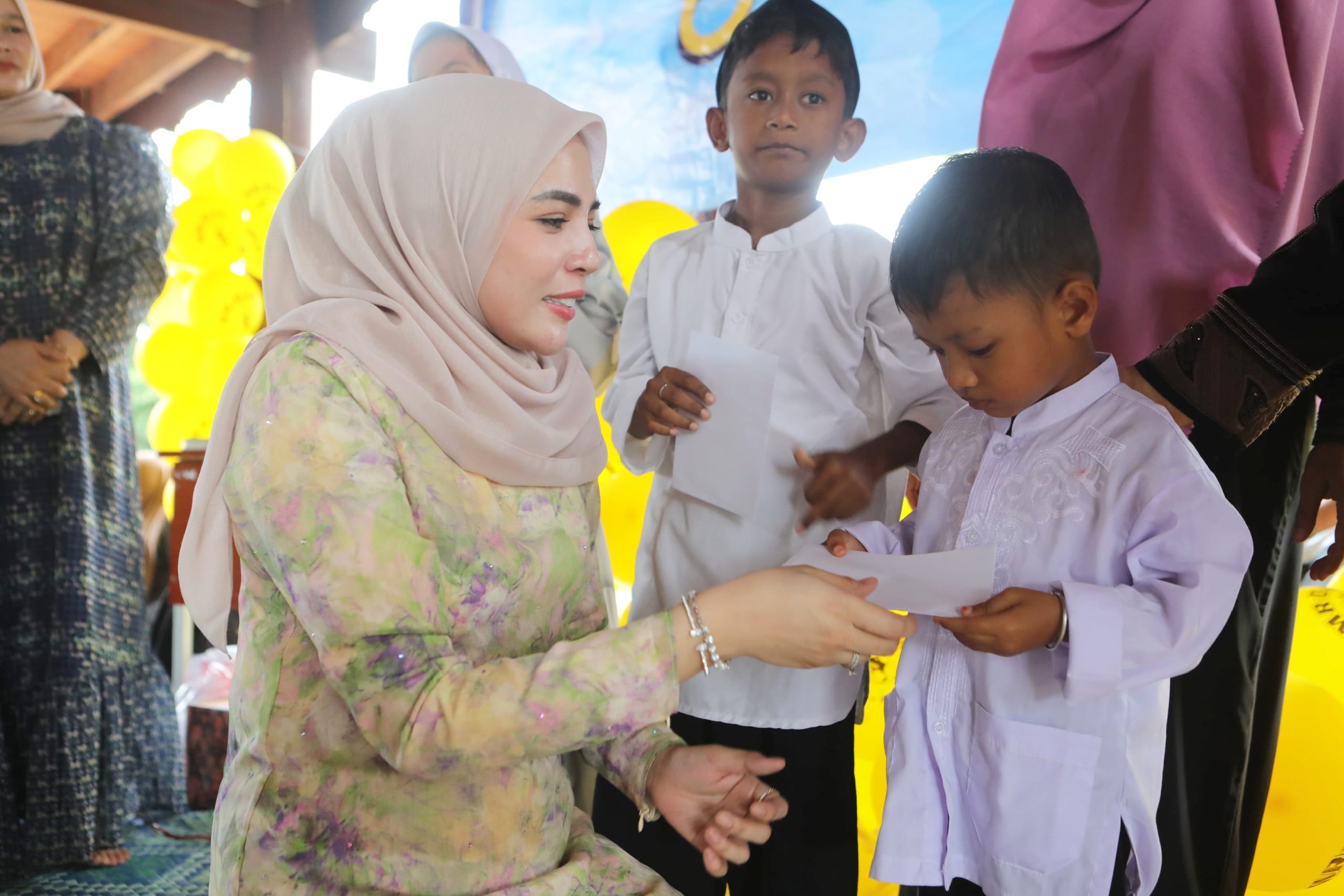 Ketua TP-PKK Kota Lhokseumawe, Ny. Yulinda Sayuti menyerahkan santunan kepada anak yatim dalam acara halalbihalal yang digelar oleh Yayasan Abulyatama Indonesia (YAI) Cabang Lhokseumawe, di Museum Kota Lhokseumawe, Minggu, 20 April 2025. (Foto: Humas Pemko)
