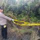 Personel kepolisian memasang garis polisi di tempat kejadian perkara (TKP)