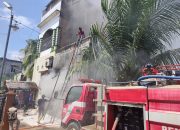 Warga membantu petugas pemadam kebakaran menjinakkan api yang menghanguskan Toko Kain Bahgia Tex di Tanah Jambo Aye, Aceh Utara