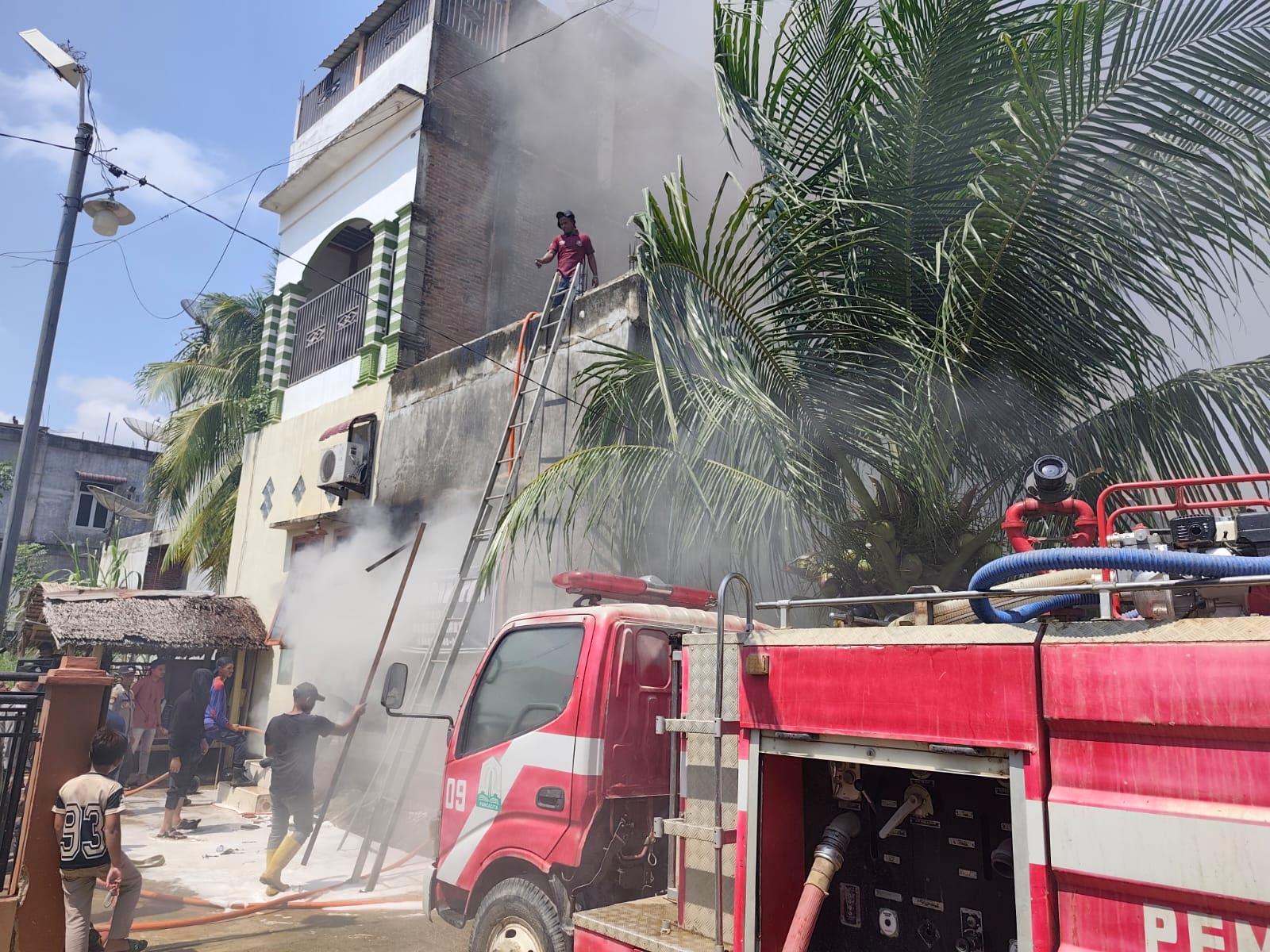 Warga membantu petugas pemadam kebakaran menjinakkan api yang menghanguskan Toko Kain Bahgia Tex di Tanah Jambo Aye, Aceh Utara